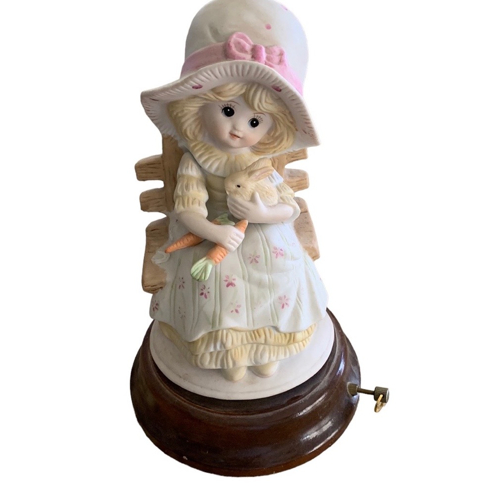 Porcelain child with bunny sitting on bench musical plays “It’s a small world”.